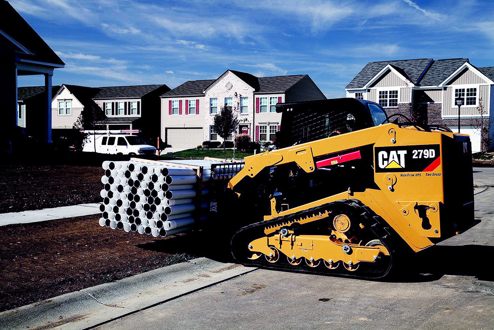 Small Bobcat carrying draining pipes